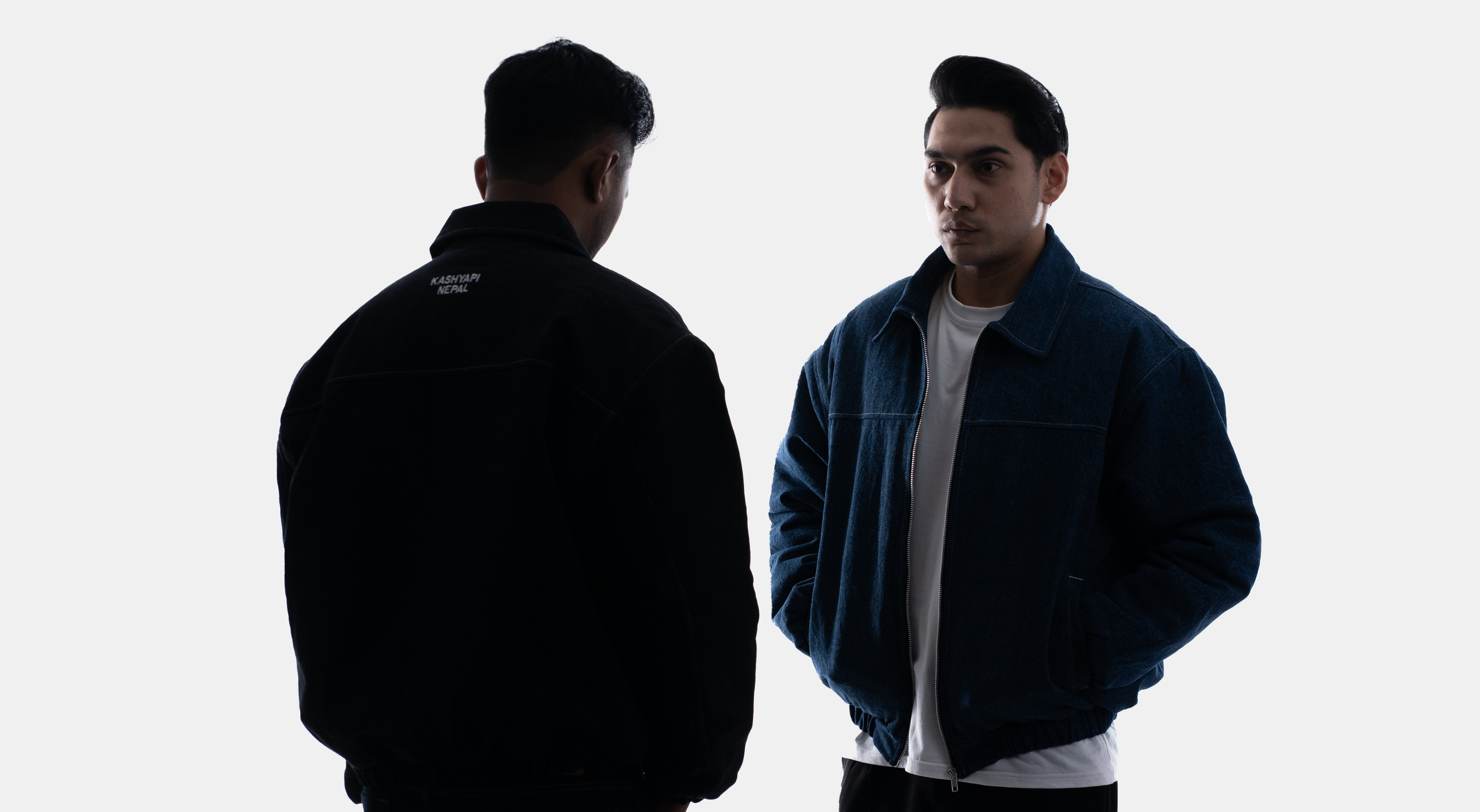 Two men standing close to each other against a white background